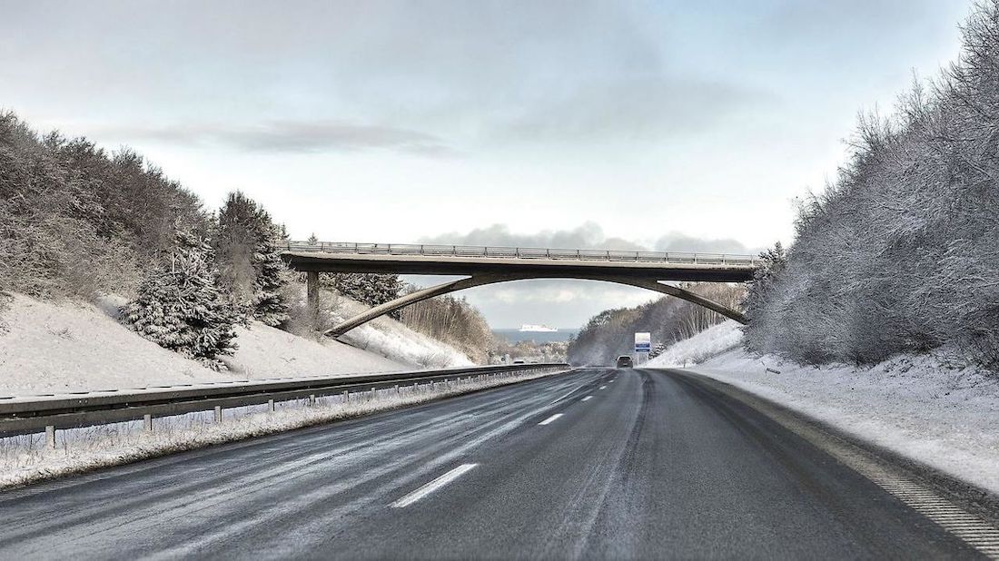 Stærkt snevejr på vej under en motorvejsbro